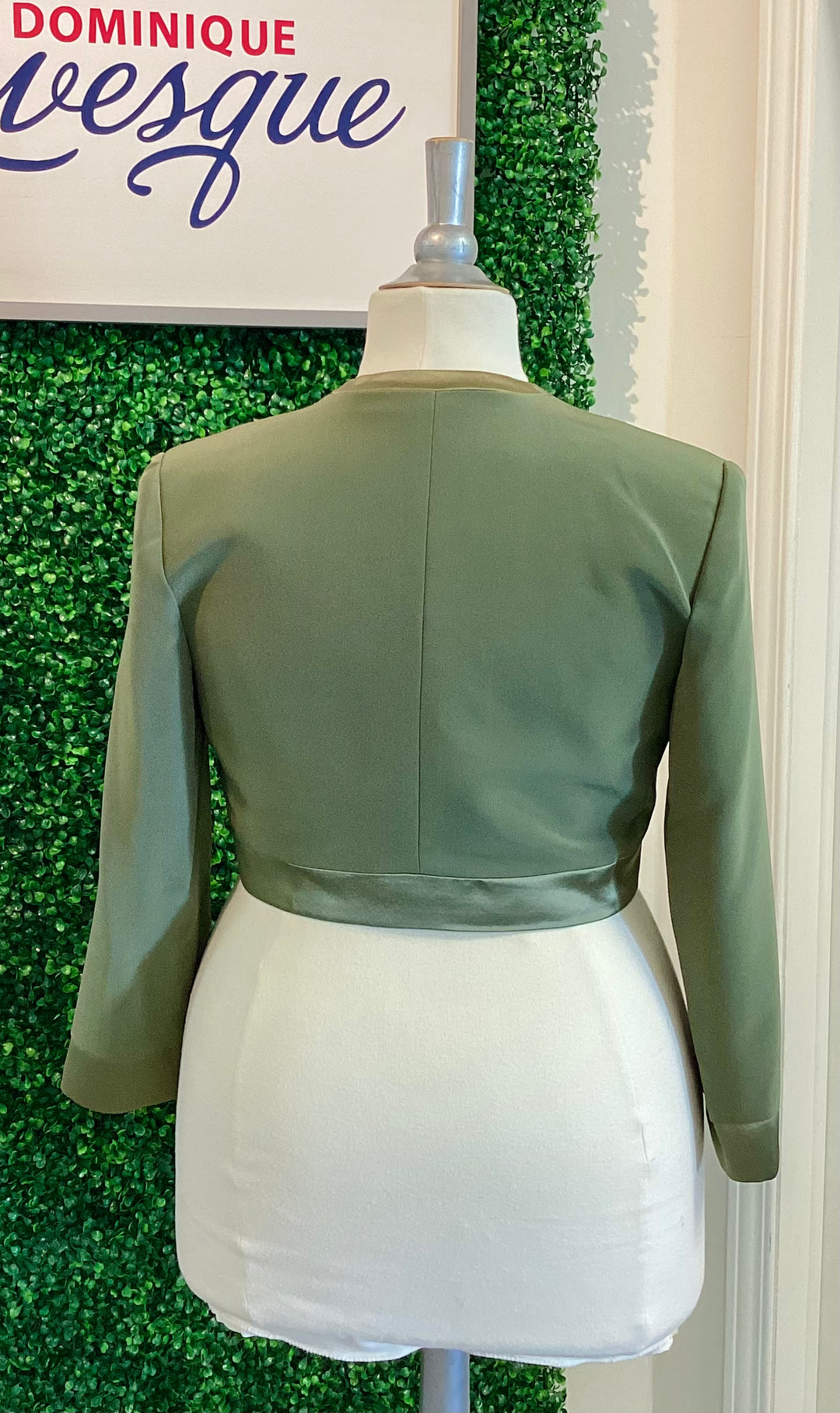 Green vest on a mannequin against a green textured wall with &