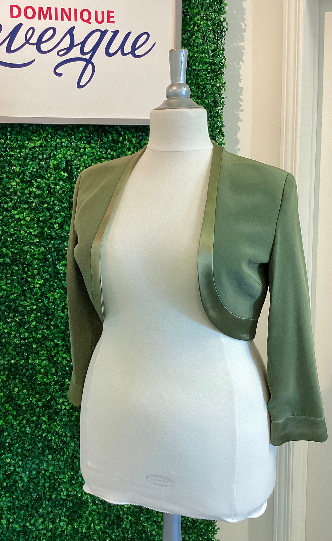 Green vest on a mannequin against a green leafy background with &