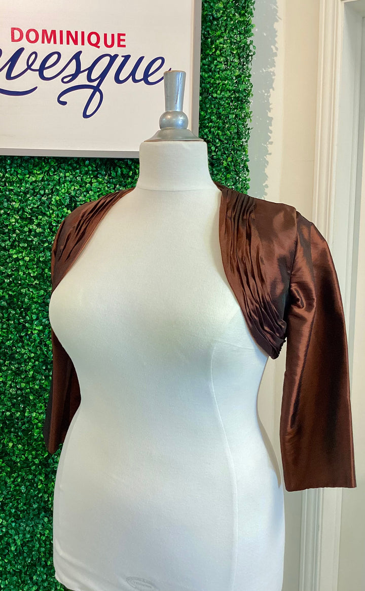 Brown satin bolero on a mannequin against a green leafy background with &
