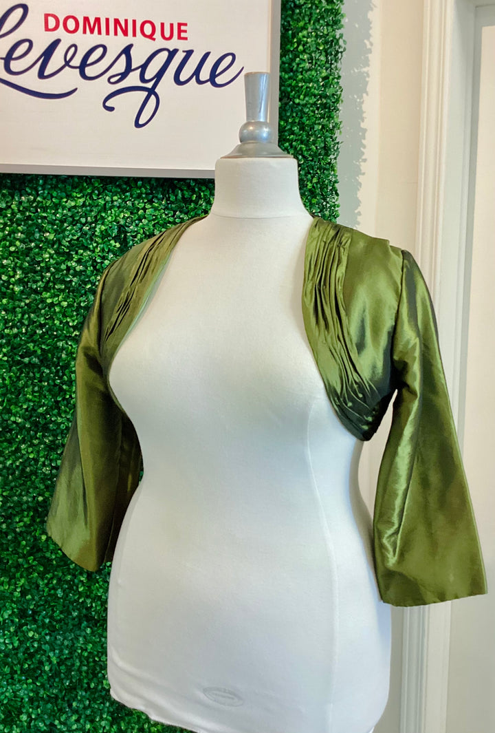 Green bolero on a mannequin against a green leafy background with &