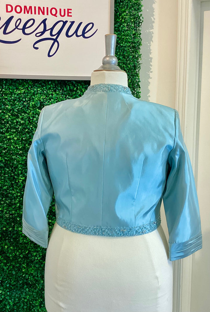 Light blue jacket on a mannequin against a green leafy background with &