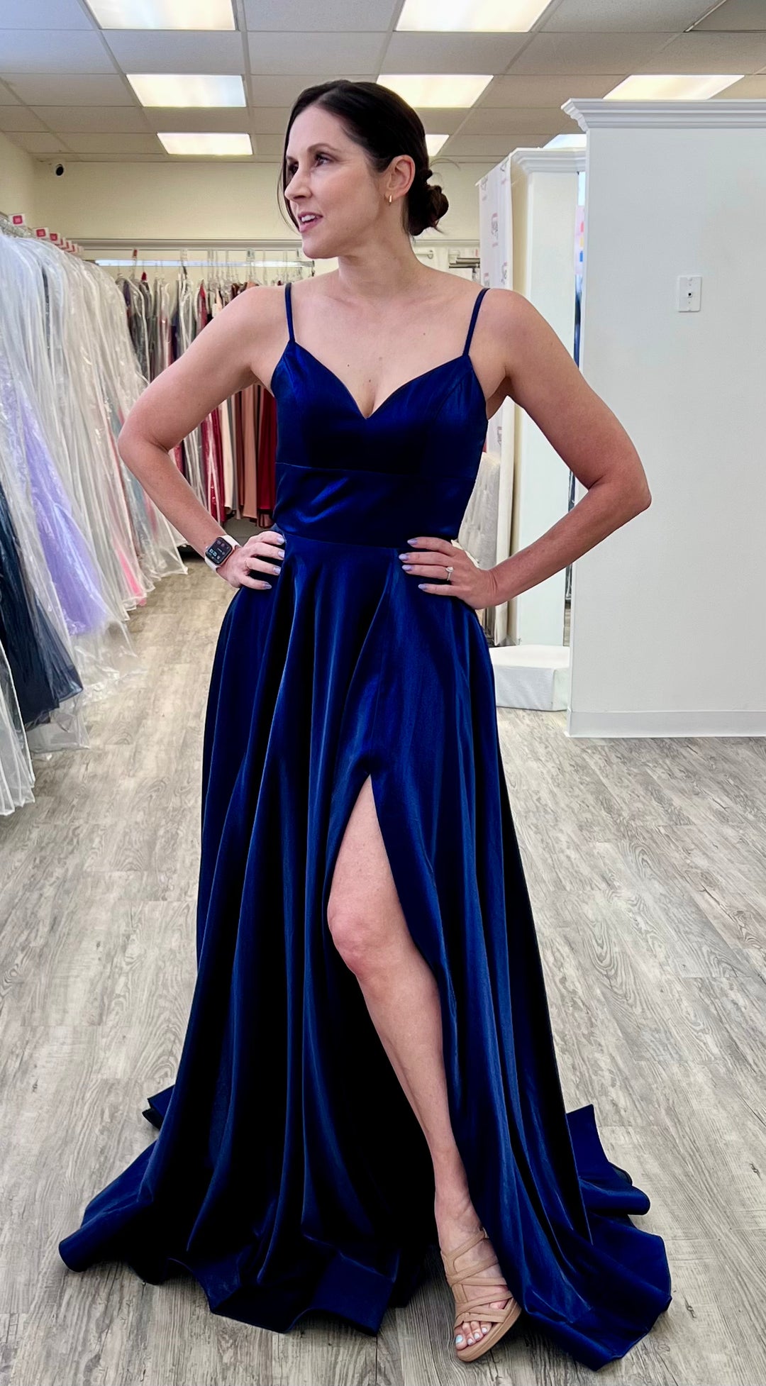 Woman wearing a blue evening gown in a fitting room.