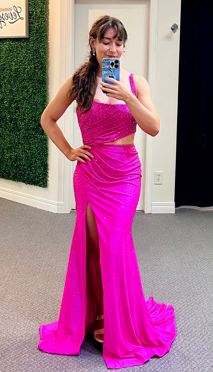 Woman wearing a bright pink dress with a slit, standing in a room with a green wall and a white door.