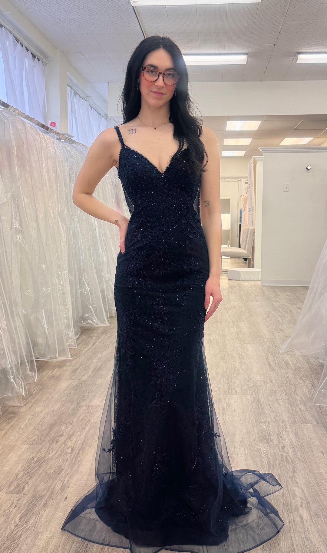 Woman wearing a navy evening gown in a fitting room.