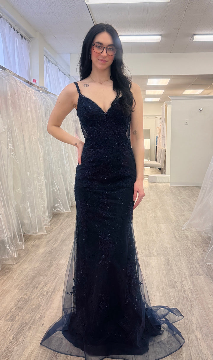 Woman wearing a navy evening gown in a fitting room.