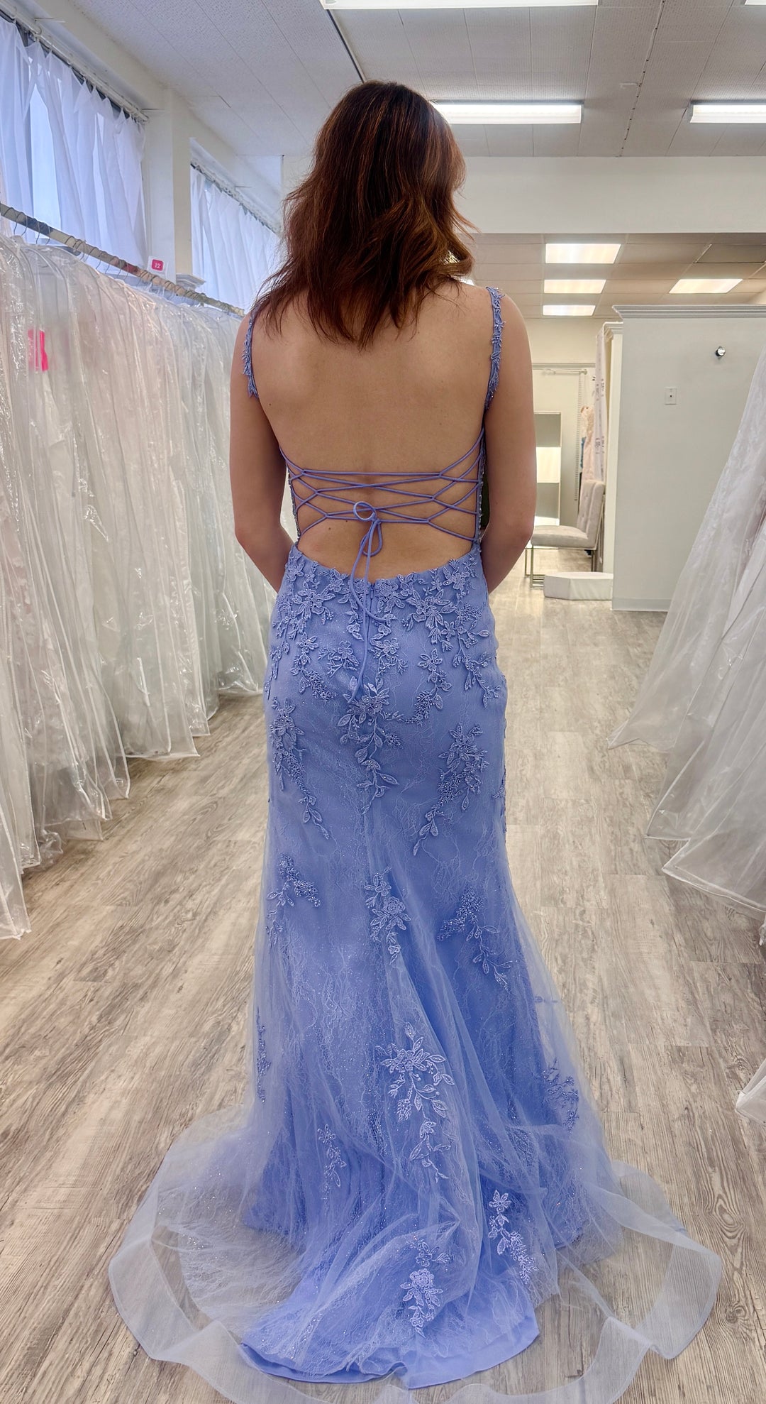 Woman wearing a peri evening gown with floral details in a store setting