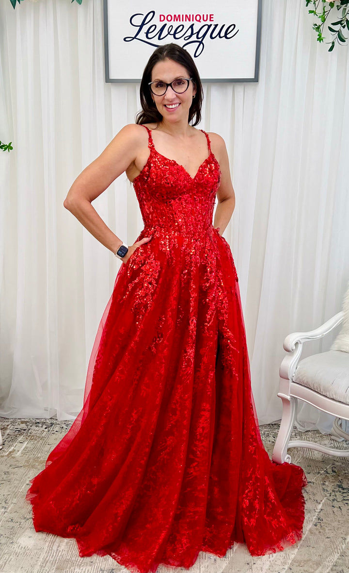 Woman wearing a red lace dress in a room with white curtains and a chair.