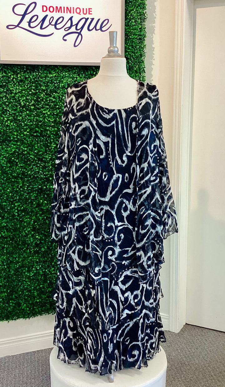 Navy and white patterned dress on a mannequin against a green wall with &