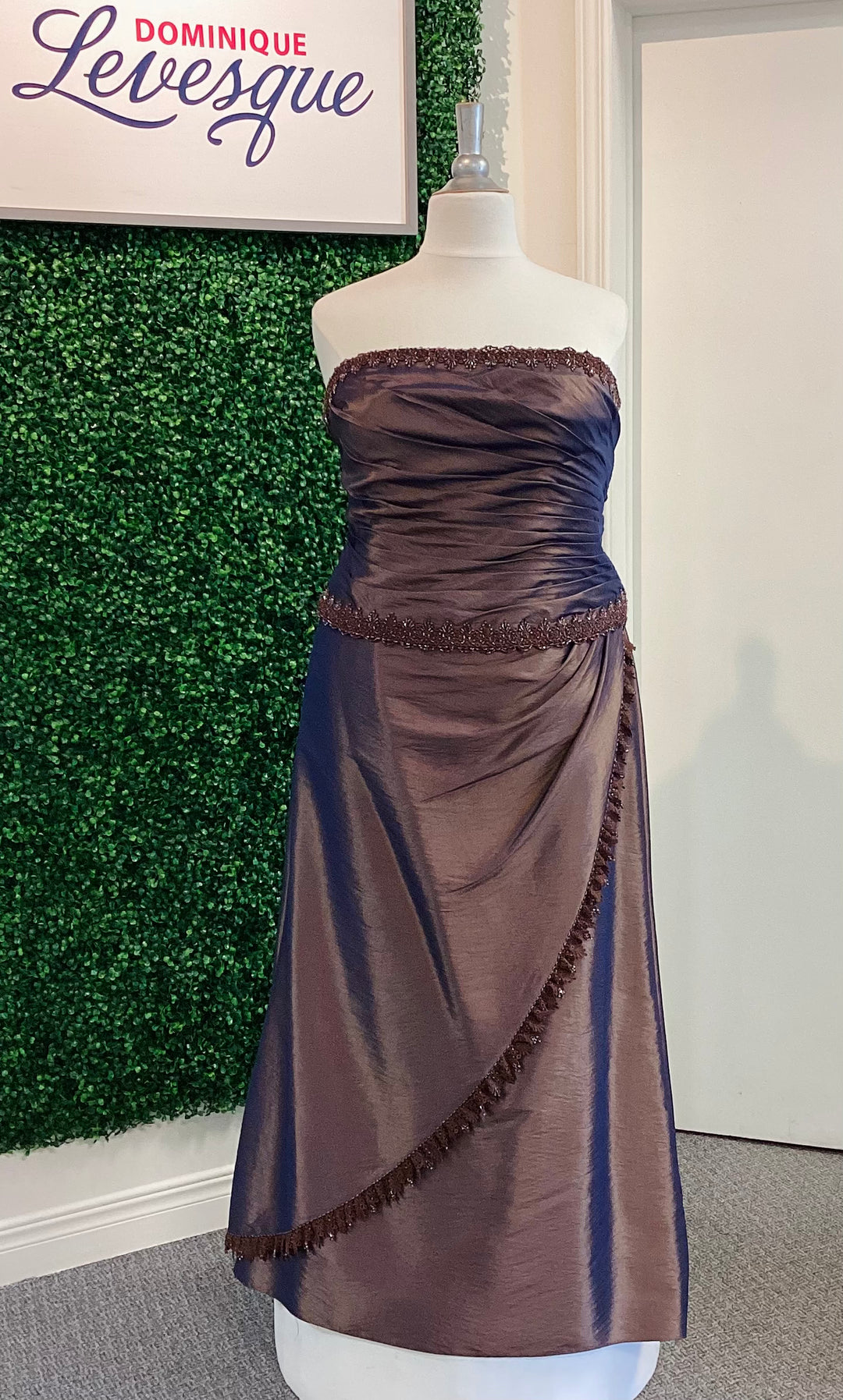 Cocoa strapless dress on a mannequin with a green leafy background and &