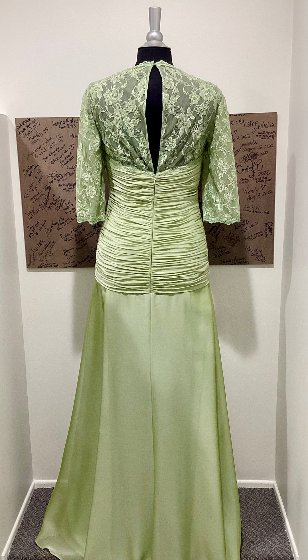 Green lace dress on a mannequin against a plain background.