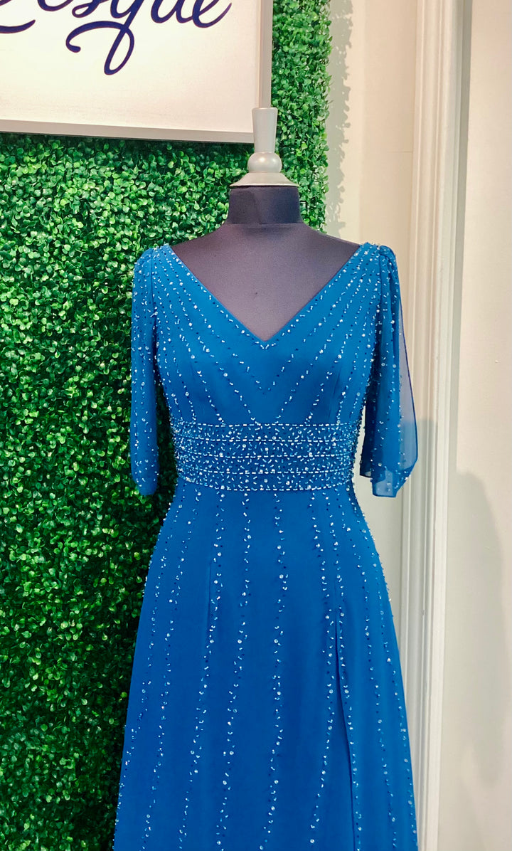 Blue evening gown on a mannequin against a green leafy background