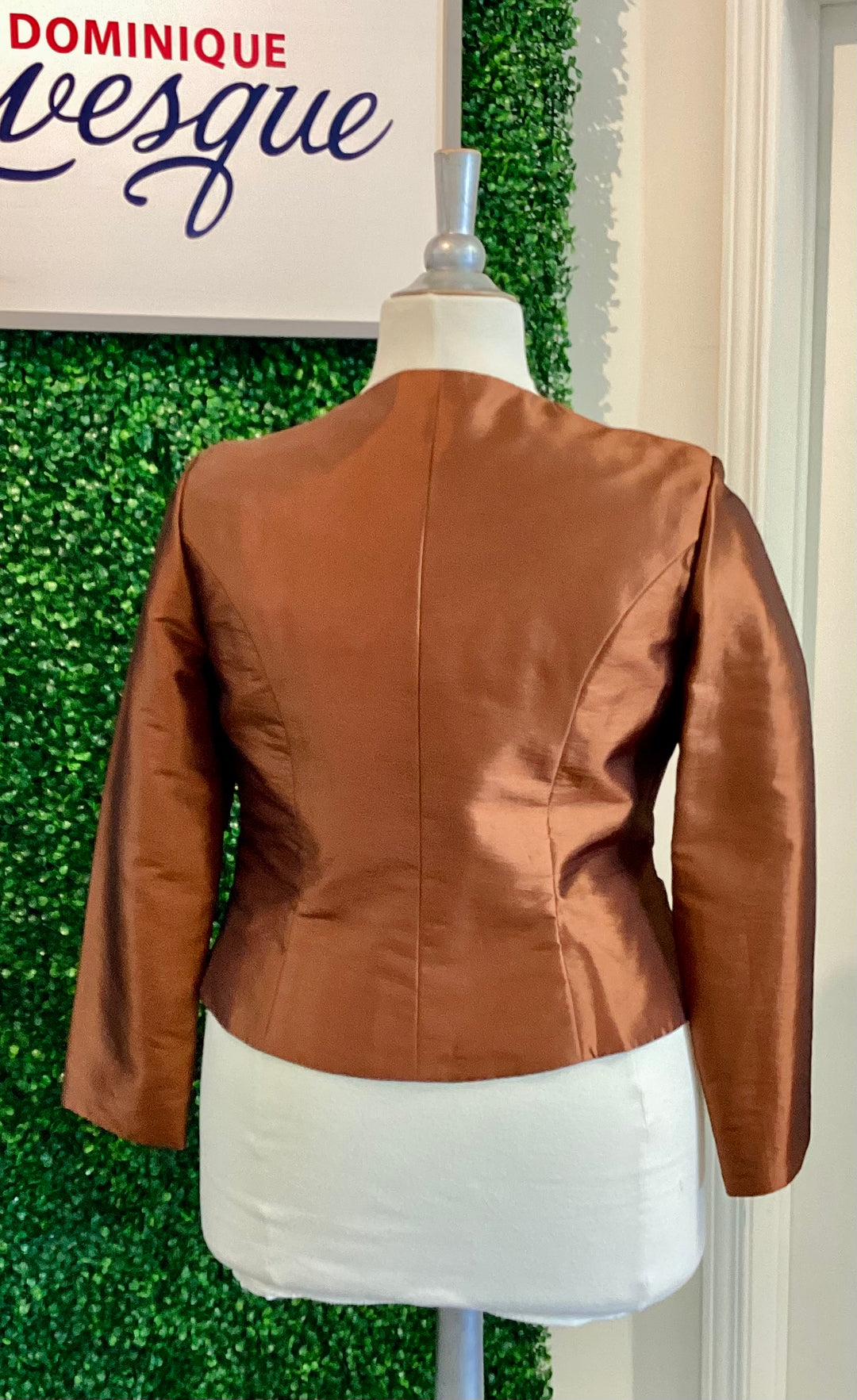 Brown jacket on a mannequin against a green leafy background with &