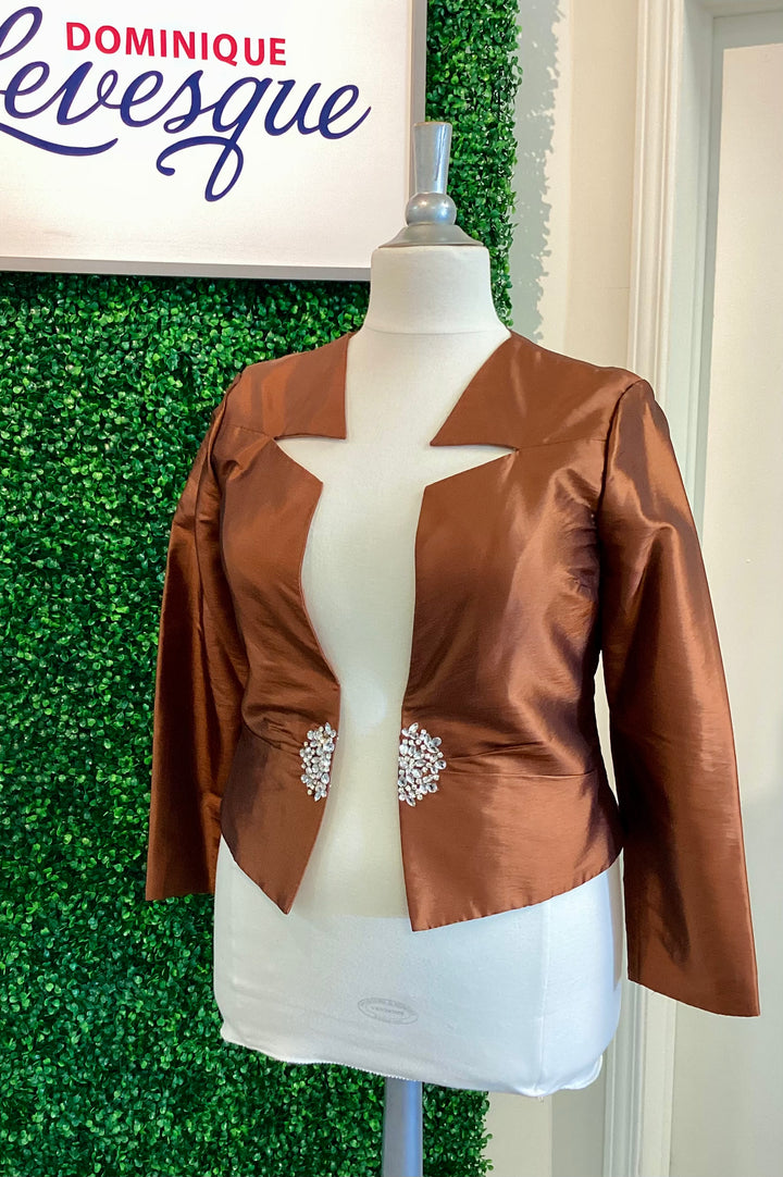 Brown satin blazer with embellishments on a mannequin against a green leafy background, featuring the brand &