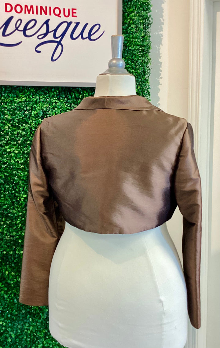 Brown jacket on a mannequin against a green leafy background with &