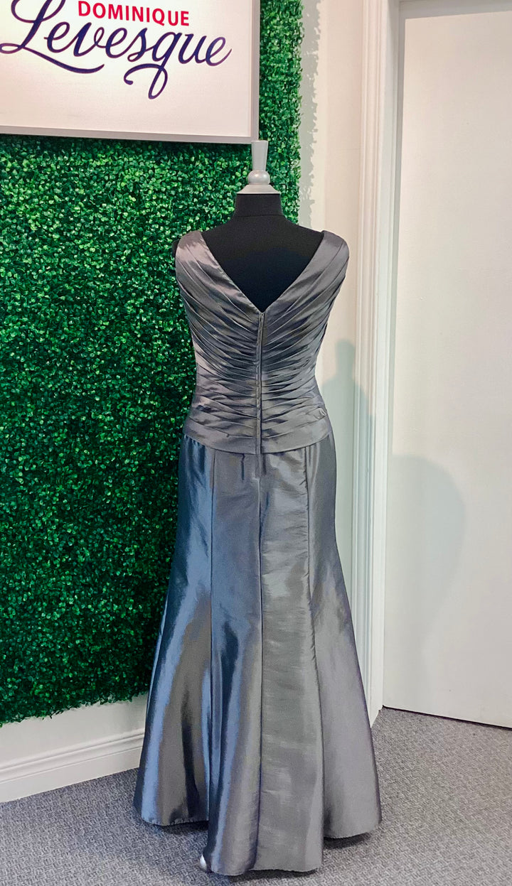Silver evening gown on a mannequin against a green textured wall with &
