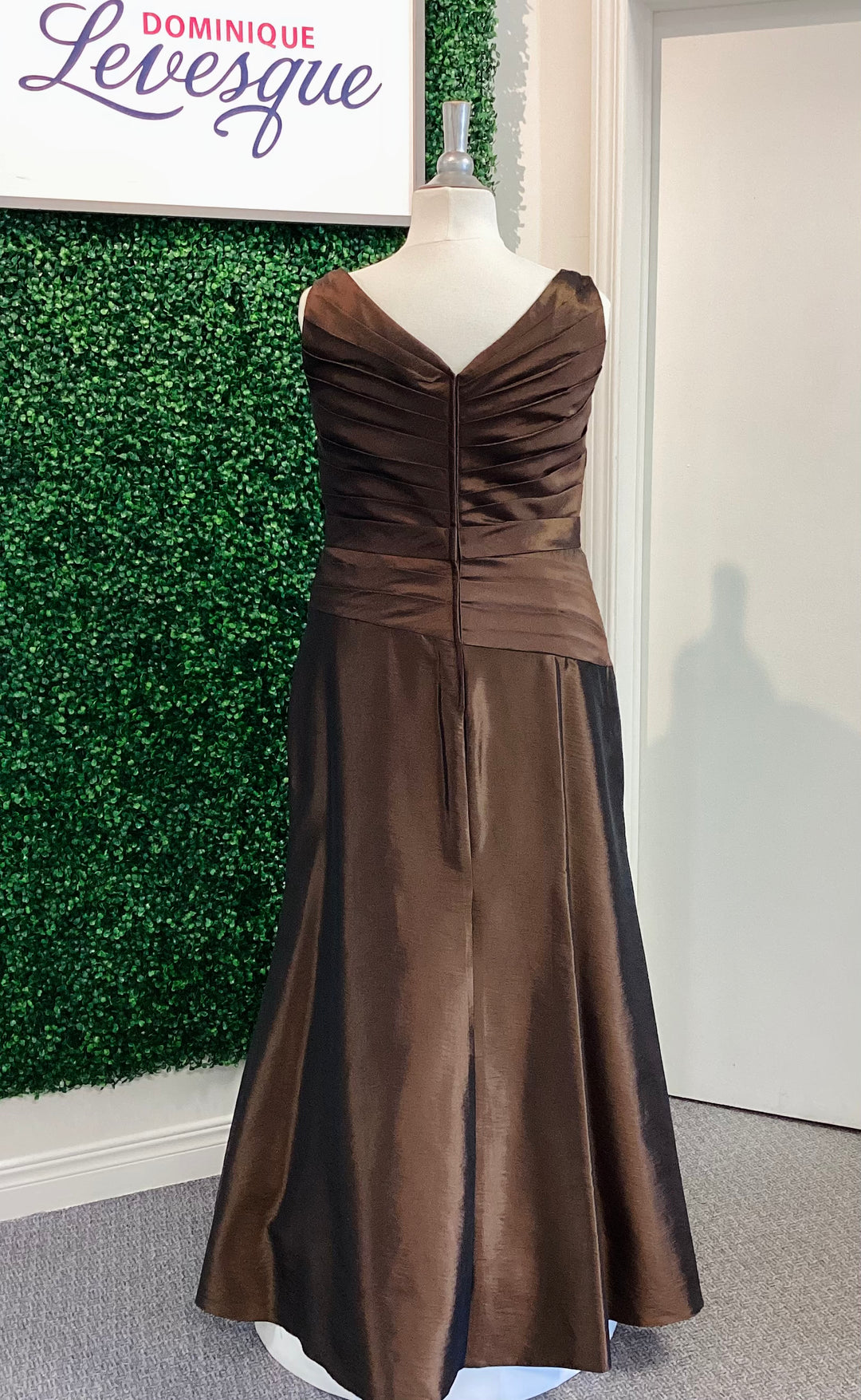 Cocoa evening gown on a mannequin against a green wall with &