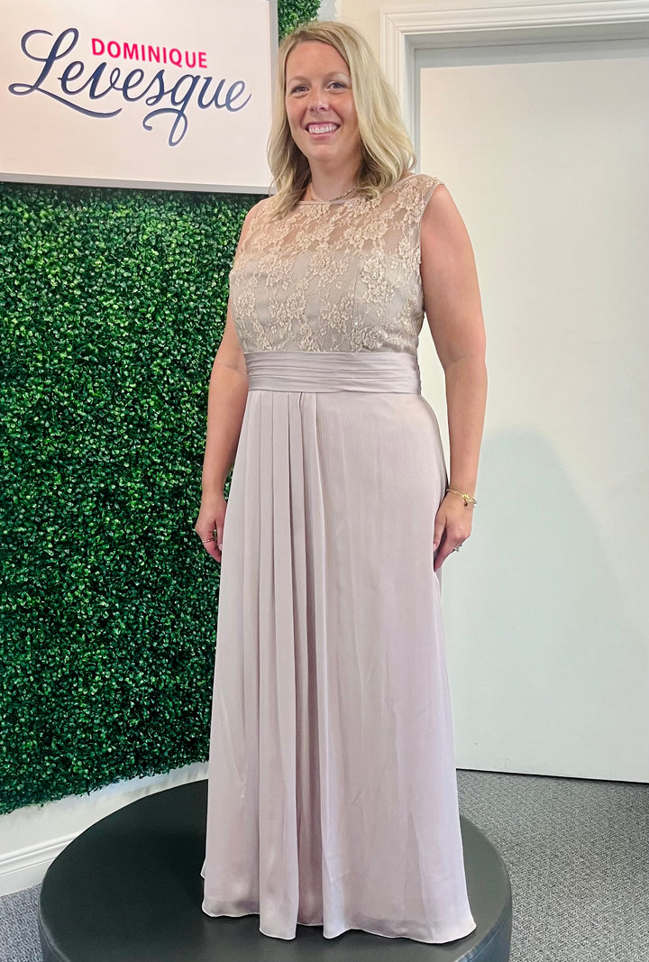 Woman wearing a long beige pink elegant dress with a green foliage background and &