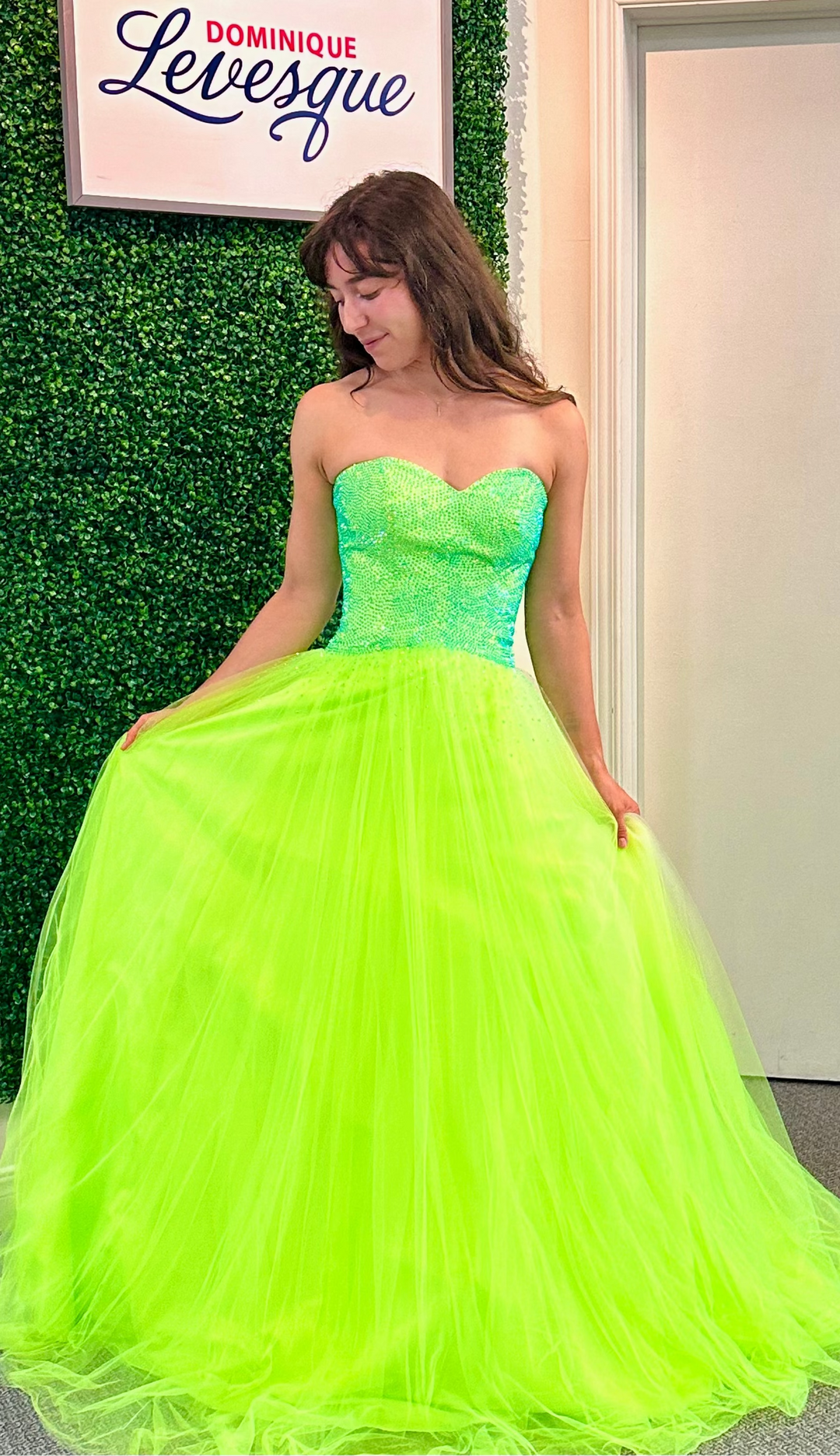 Woman wearing a lime strapless gown in an indoor setting with a green wall.