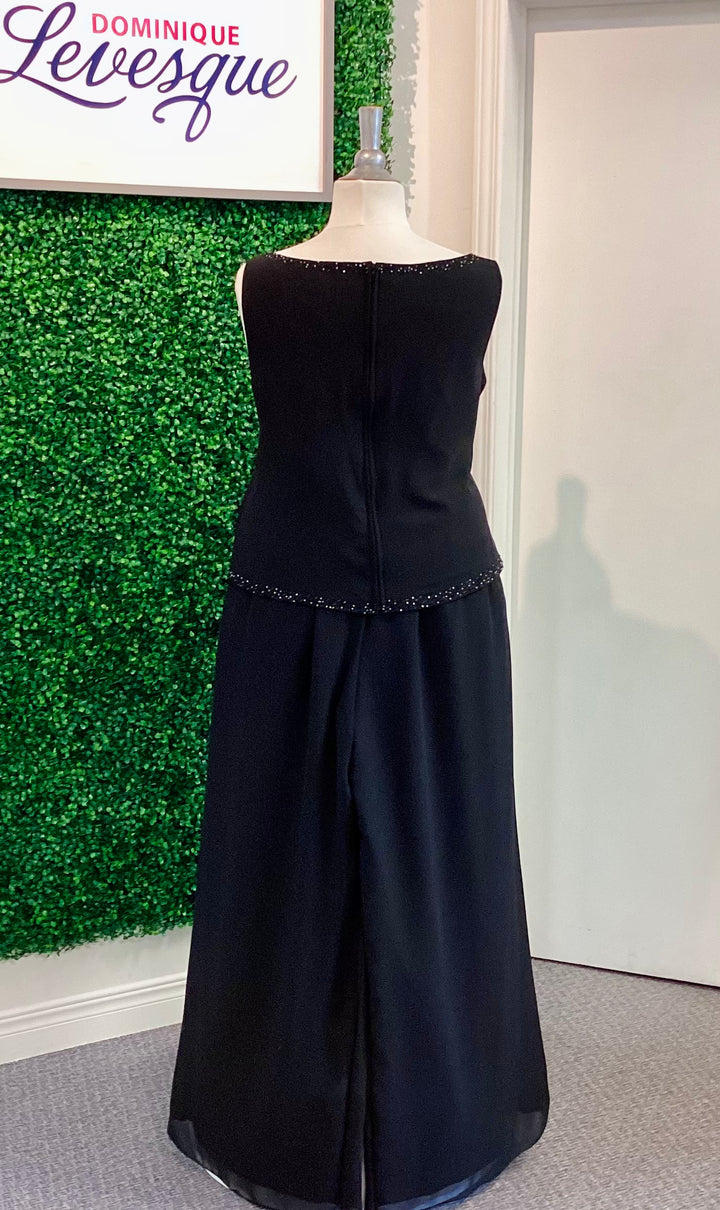Black pants and top  on a mannequin against a green wall with &