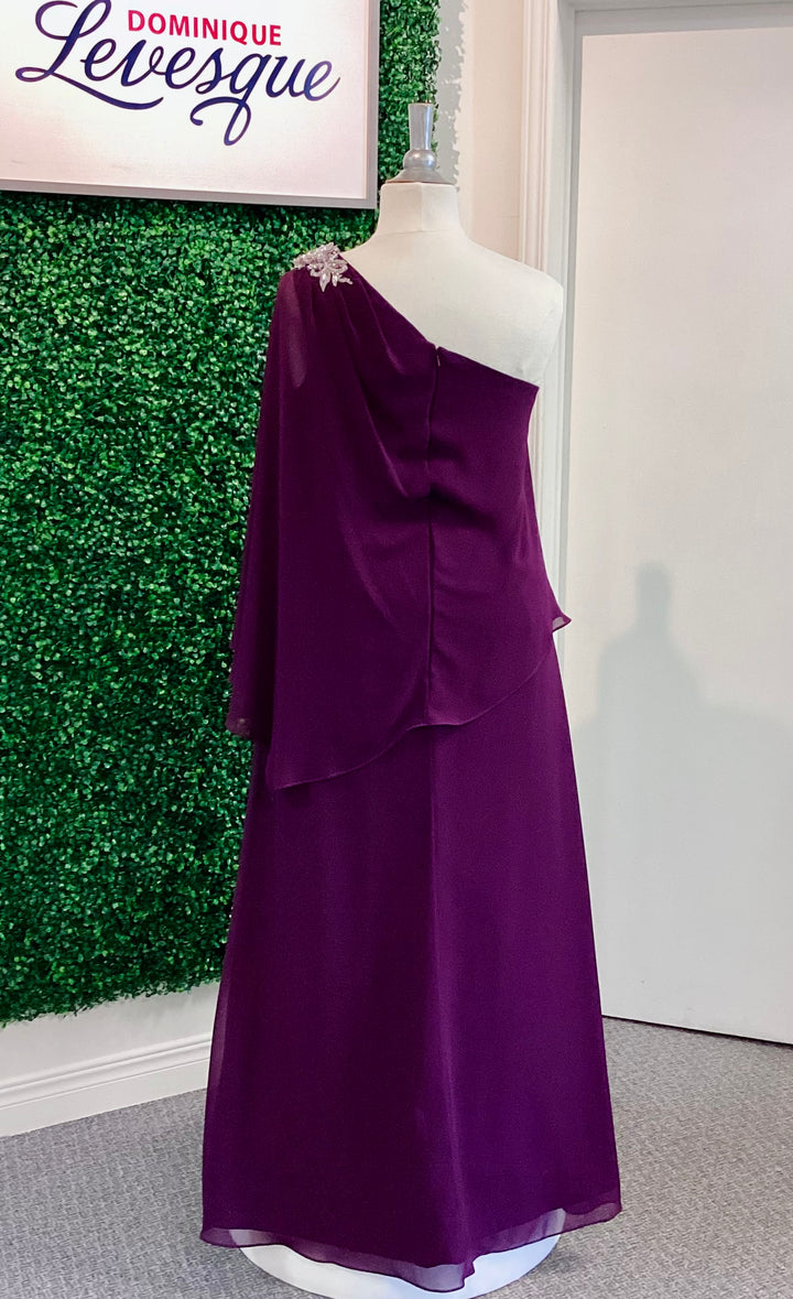 Plum one-shoulder dress on a mannequin against a green leafy background with &