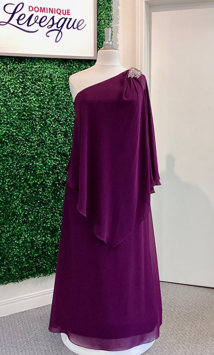 Plum one-shoulder dress on a mannequin against a green leafy background with &