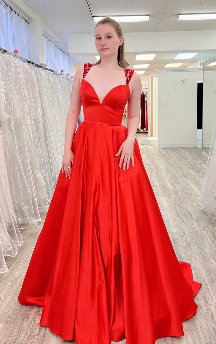 Woman wearing a red evening gown in a fitting room.