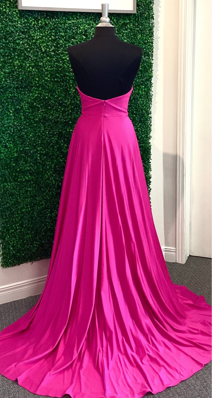 Pink evening gown on a mannequin against a green leafy background