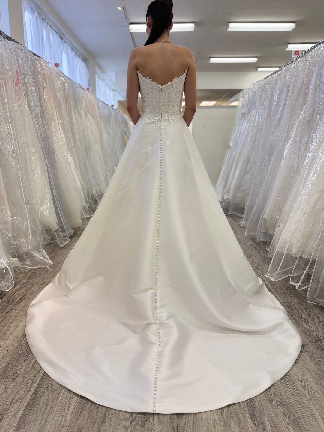 White wedding dress with a long train in a store setting