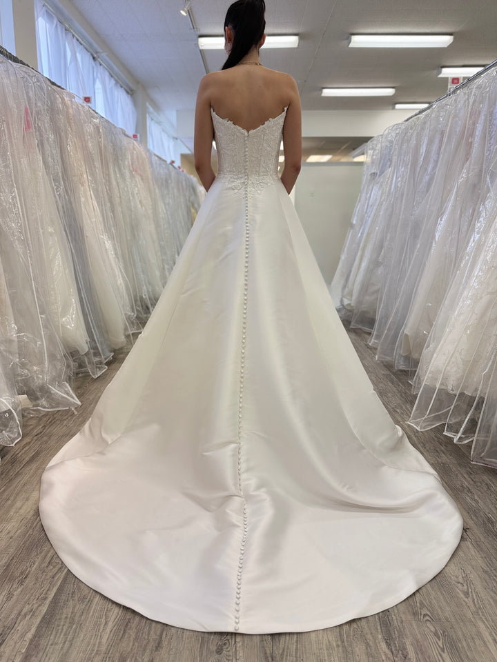 White wedding dress with a long train in a store setting