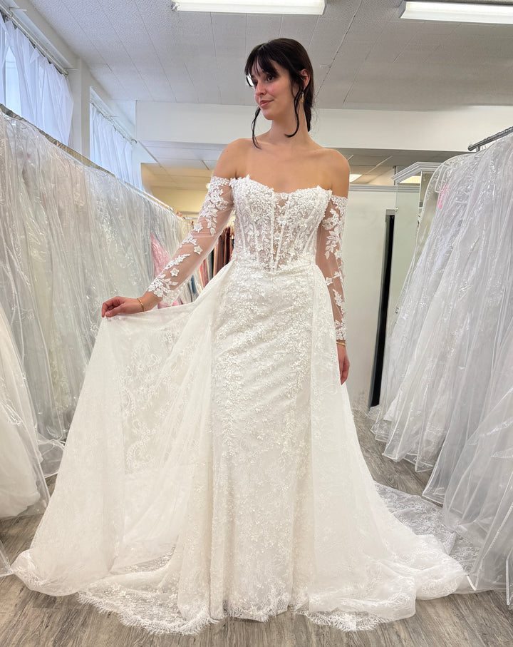 Woman trying on a white lace wedding dress in a store.