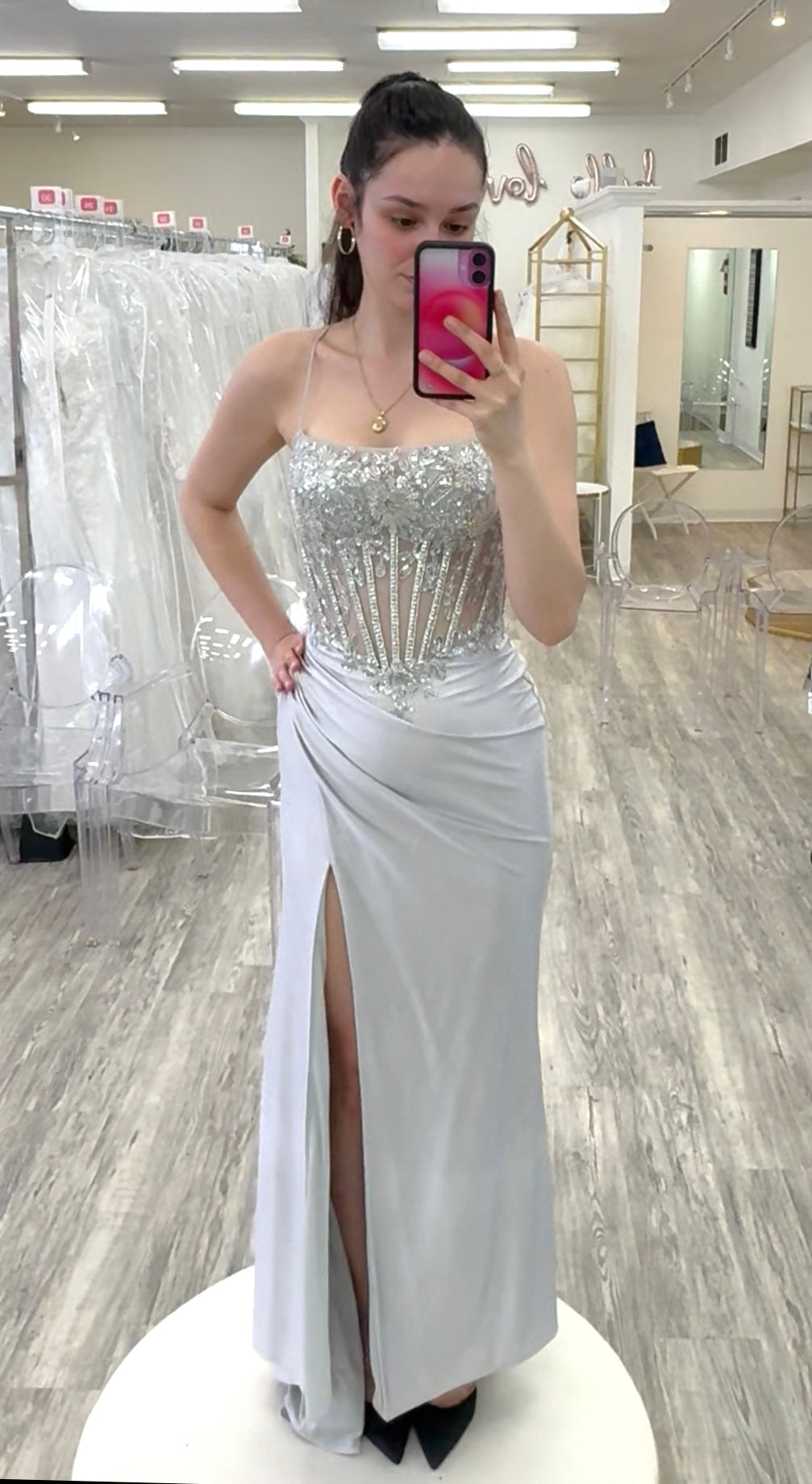 Woman wearing a silver evening gown in a store setting.