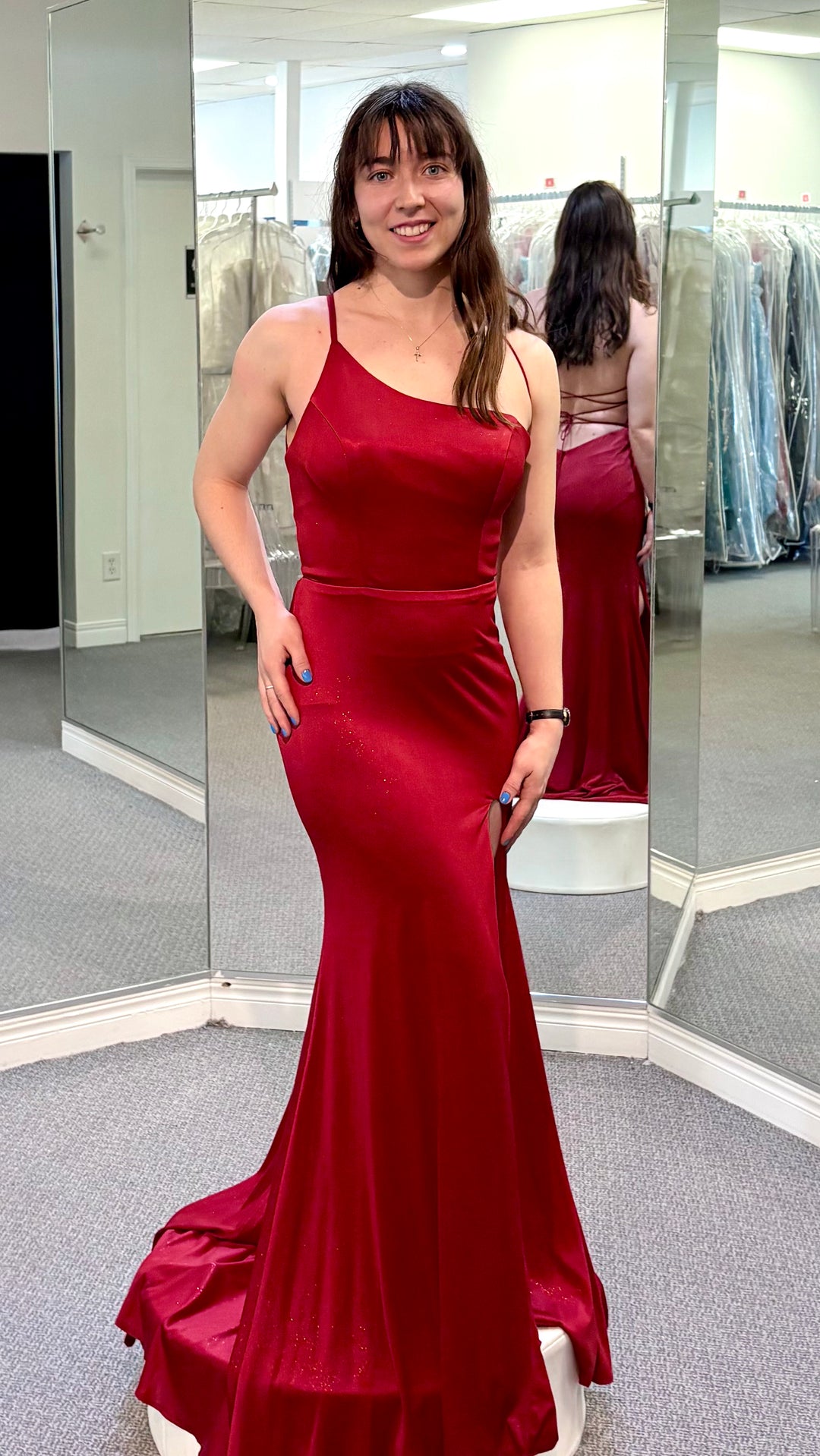 Woman in a red dress in a fitting room setting.