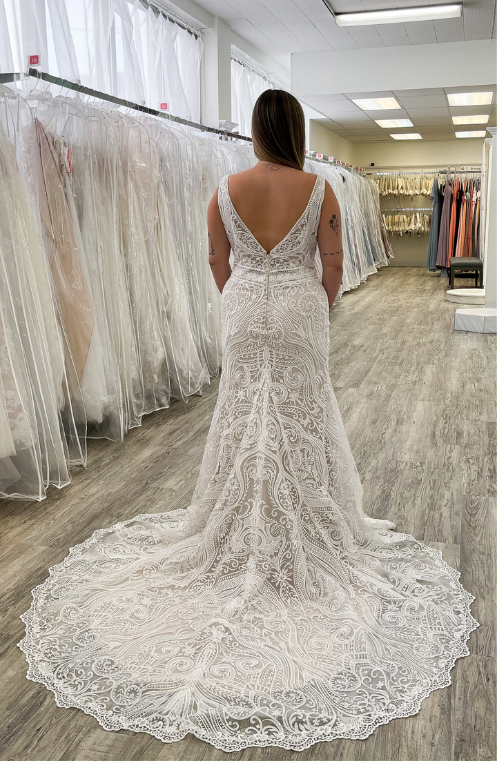 Woman wearing a white lace wedding dress in a bridal shop.