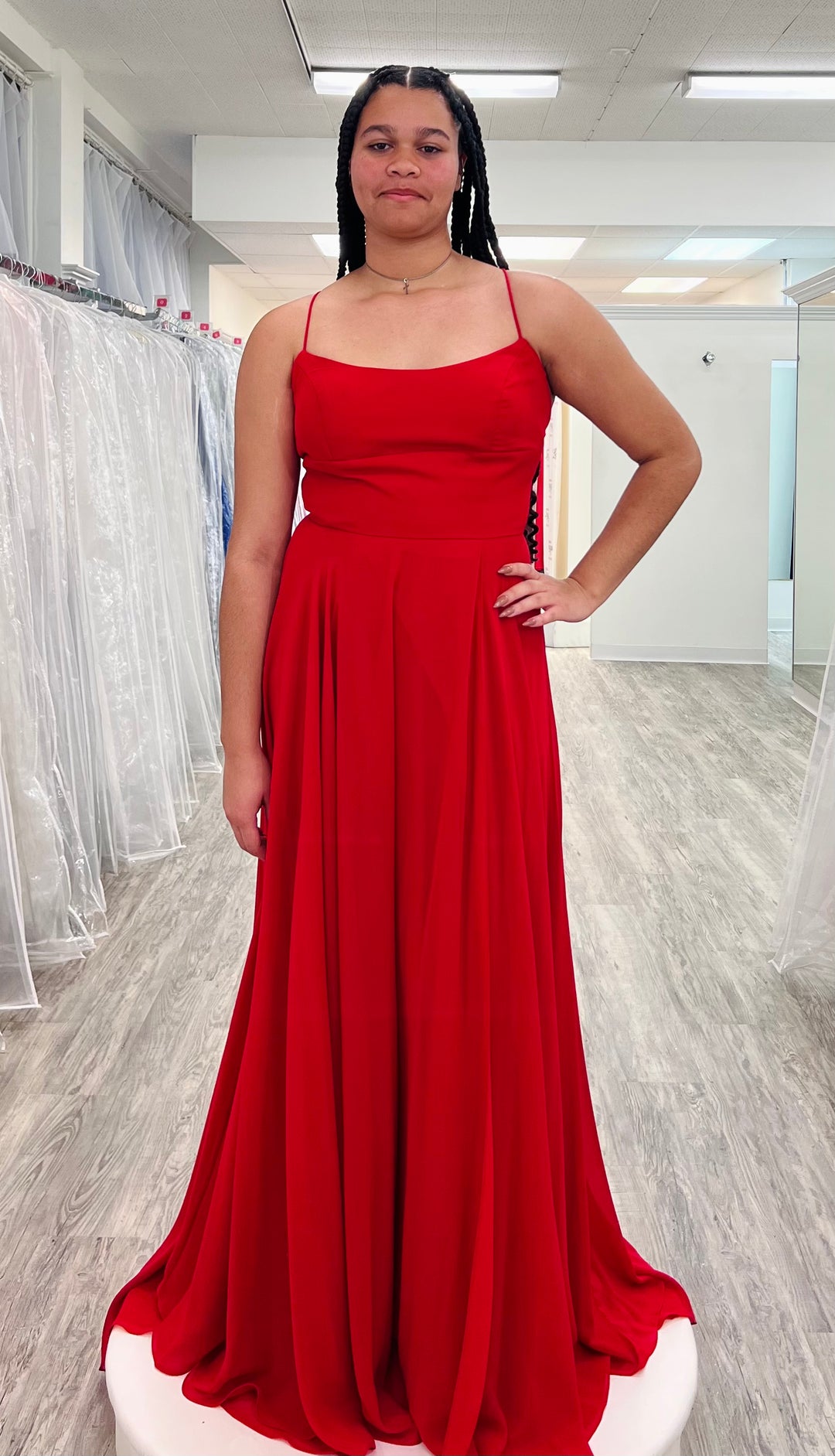 Woman wearing a red dress in a fitting room.