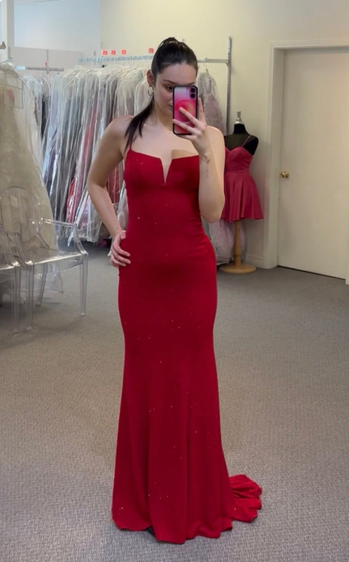 Women wearing a red dress in a fitting room with mirrors and clothing racks.