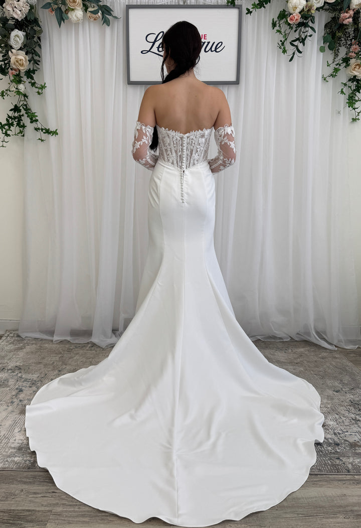 White off-shoulder wedding dress with lace details in a decorated setting.