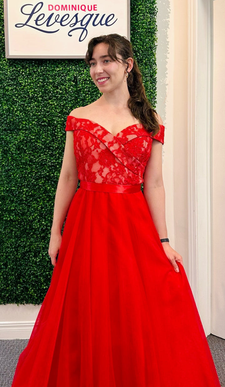 Woman in a red dress standing against a green leafy background with &