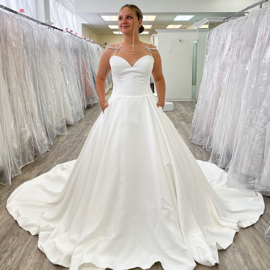 Woman wearing a white wedding dress in a store with other dresses in the background