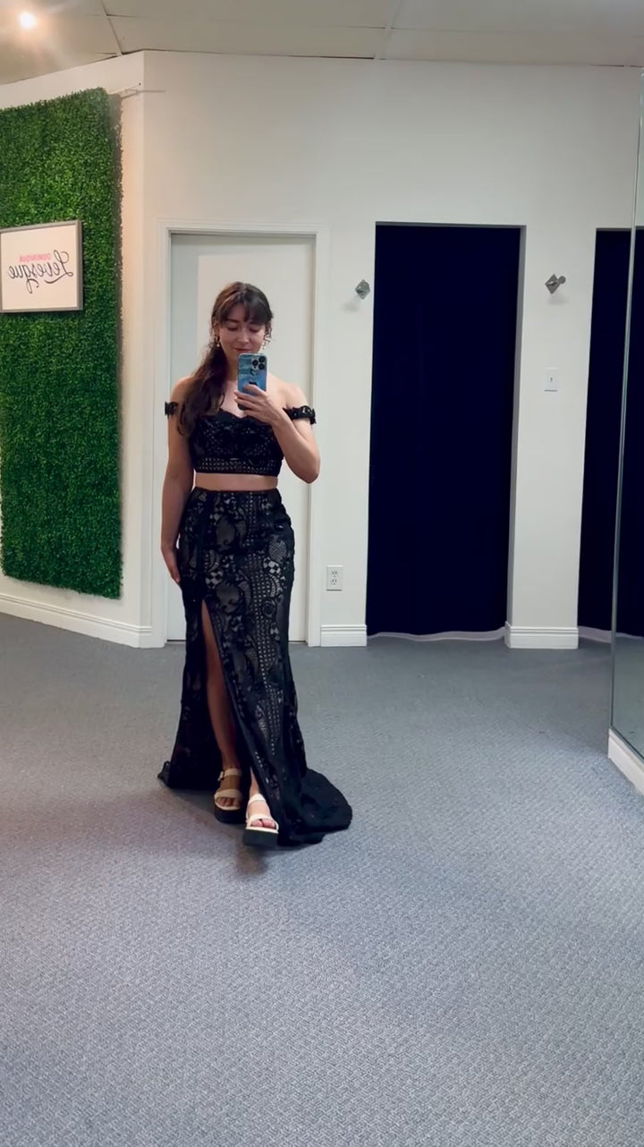 Woman taking a mirror video wearing a two piece black lace outfit in a change room.