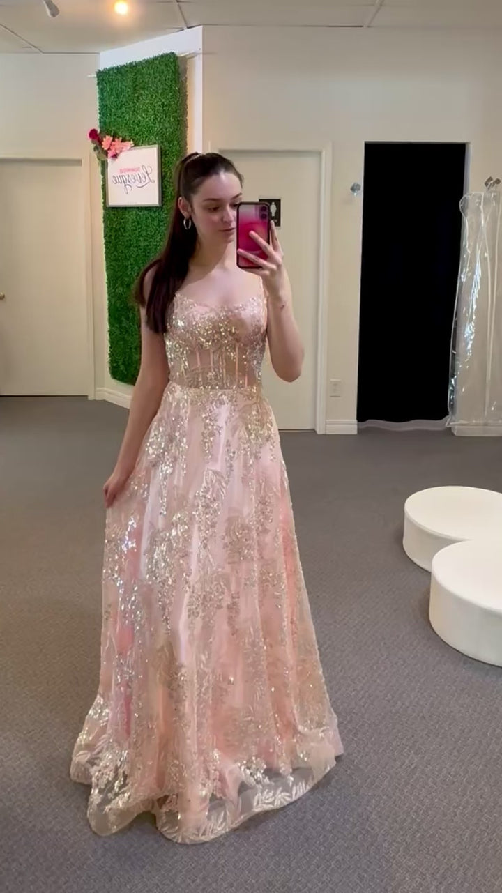 Woman wearing a long, light pink dress with floral details in a room.