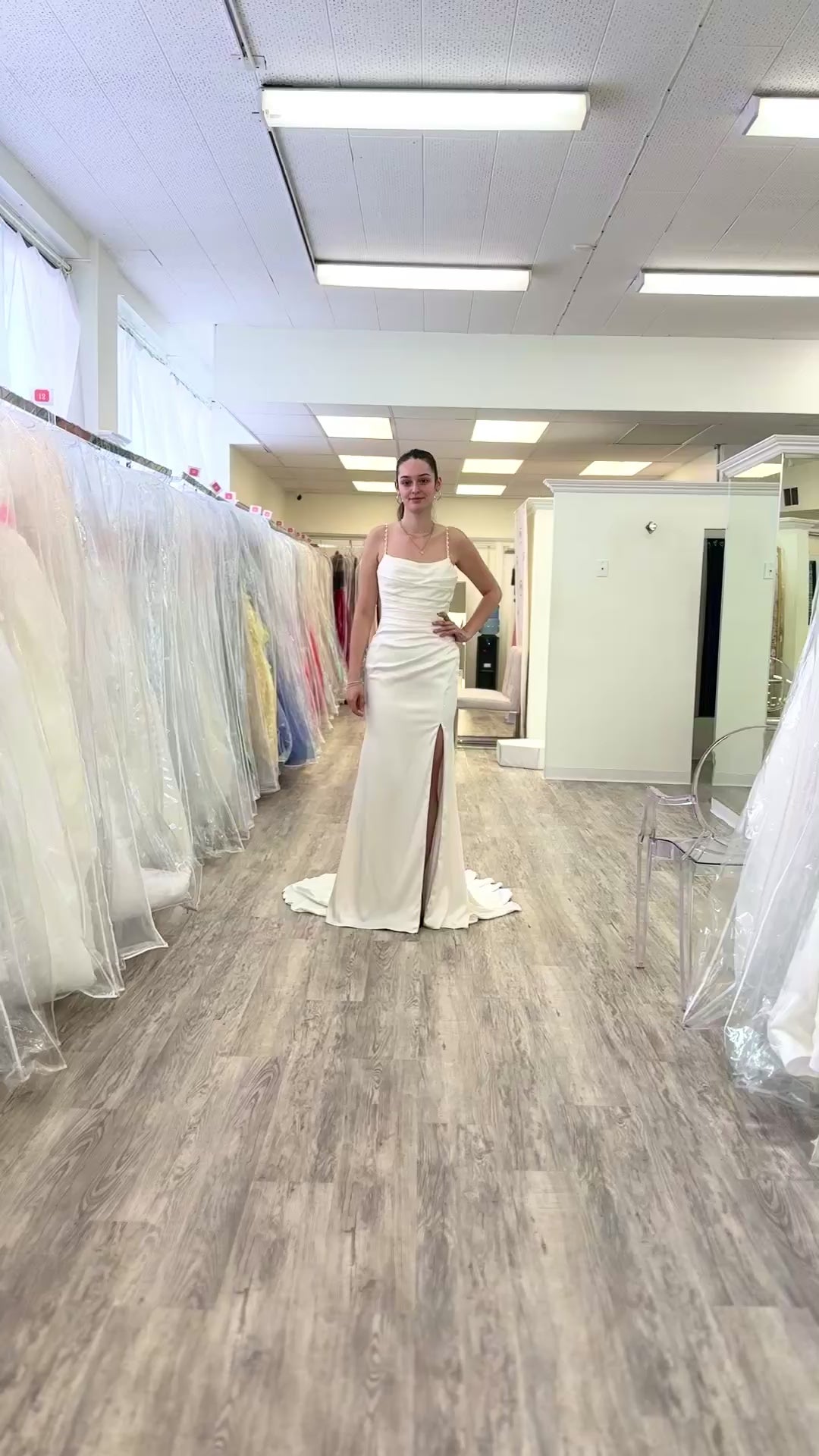 women walking in a slim wedding dress with a slit. In a store