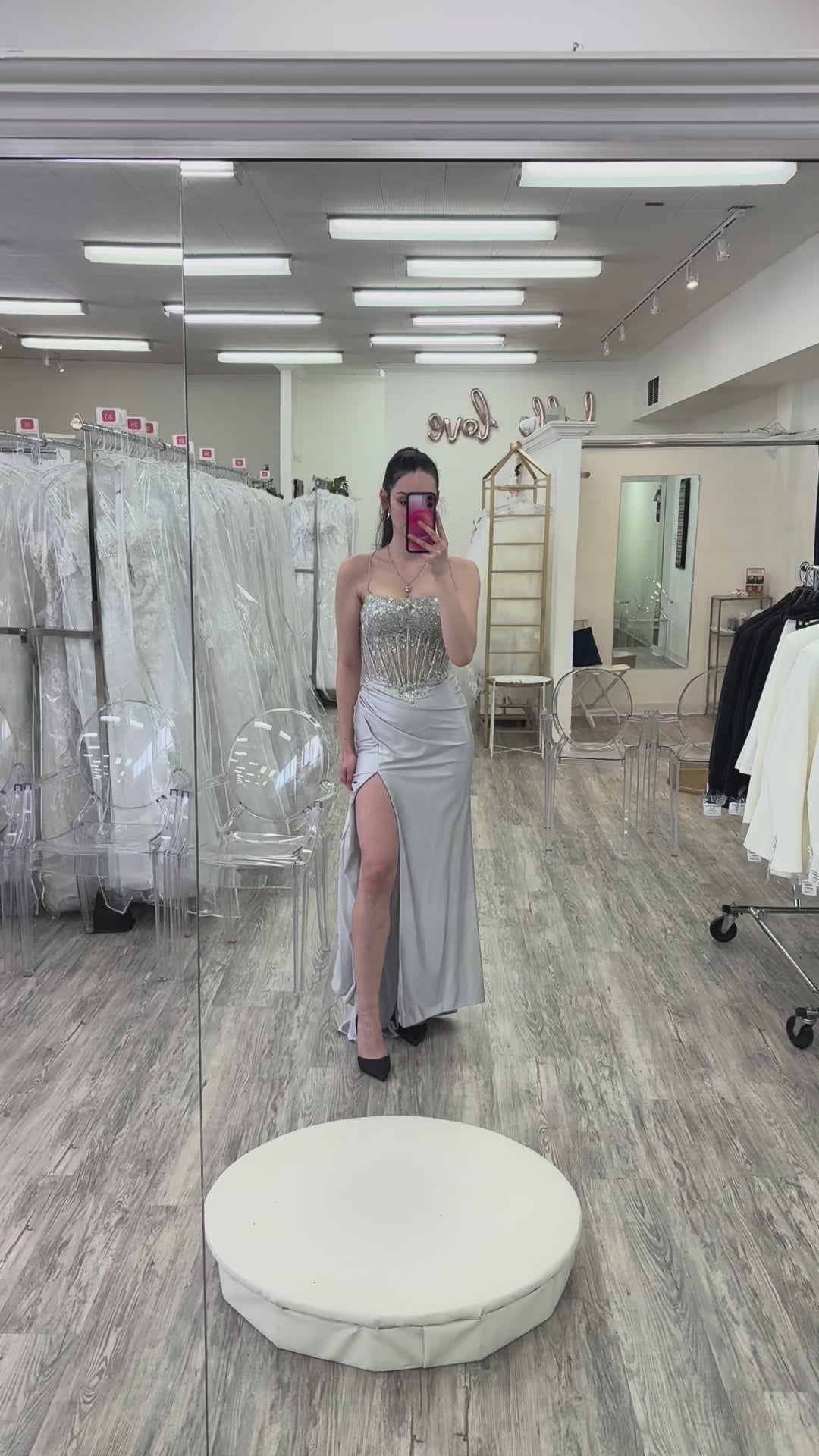 Woman wearing a silver evening gown in a store setting.