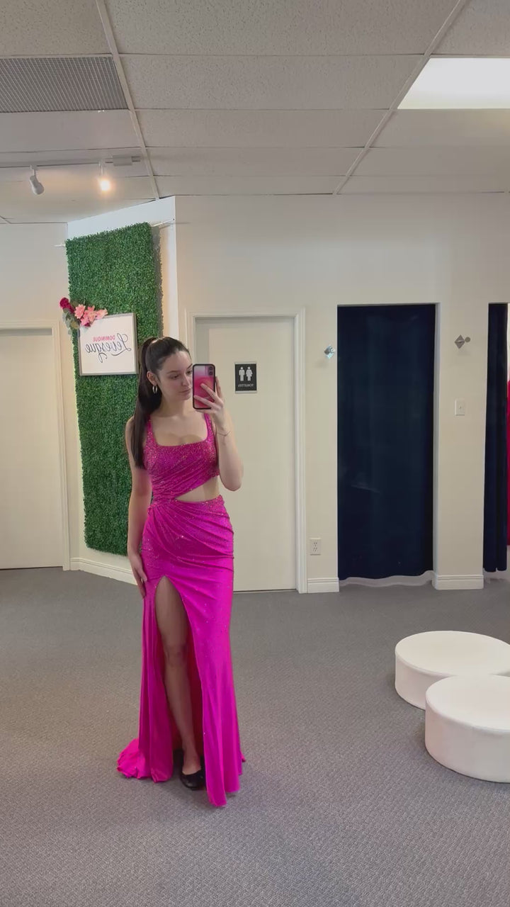 Woman wearing a bright pink dress with a slit, standing in a room with a green wall and a white door.